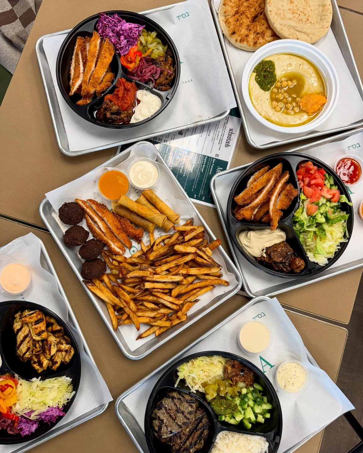 A spread of Kapara schnitzels, falafel, fries, hummus, and sides ready for pickup